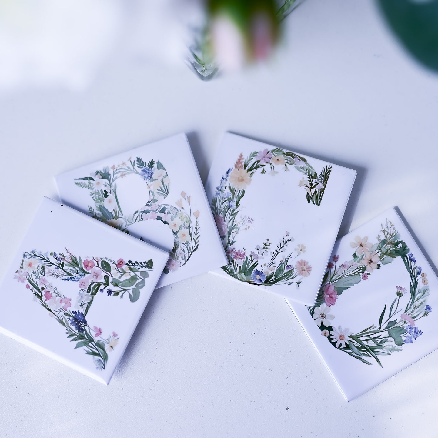Four fridge magnets with floral designs on a white surface.