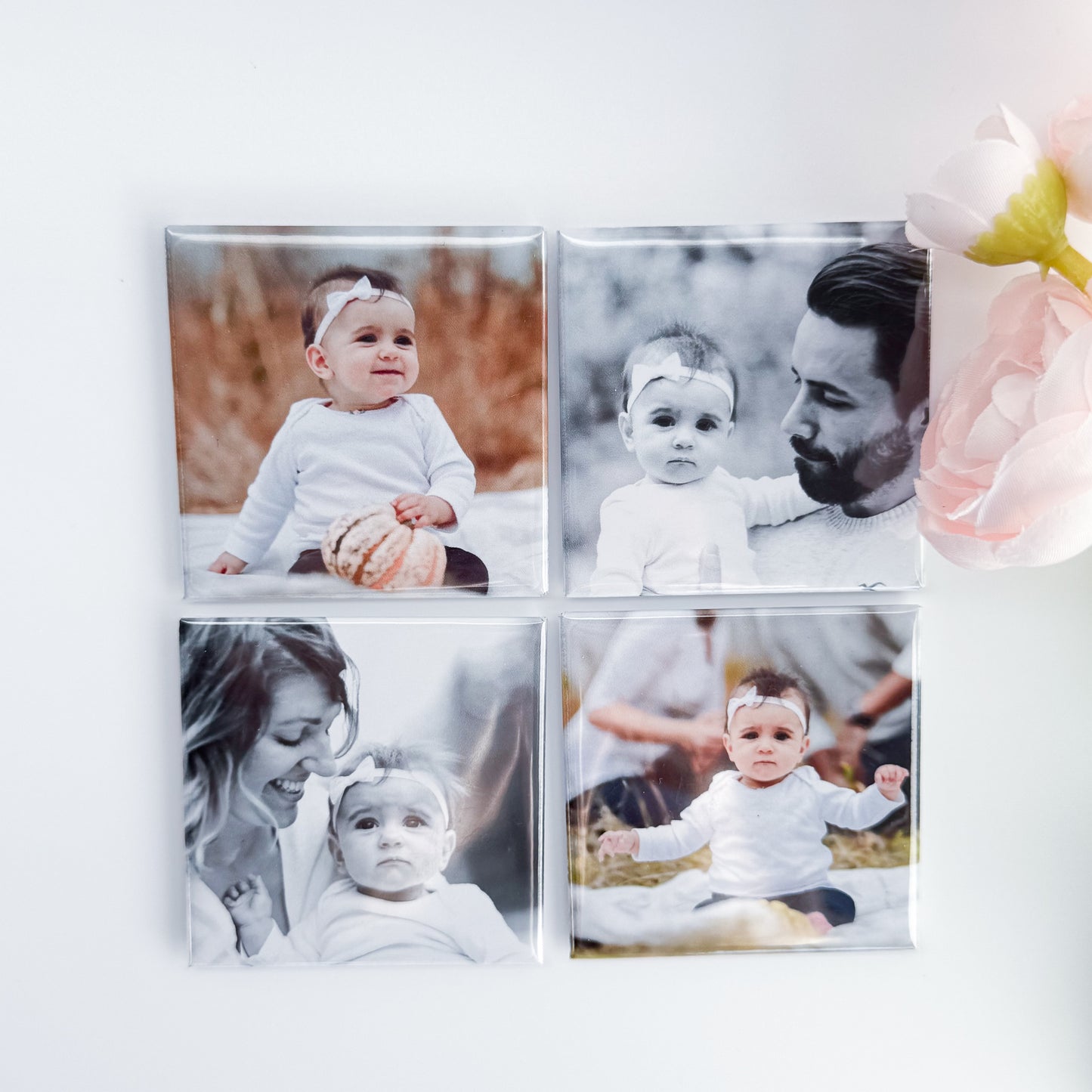 Four photo magnets on a white surface with images of a baby and a man and a woman.