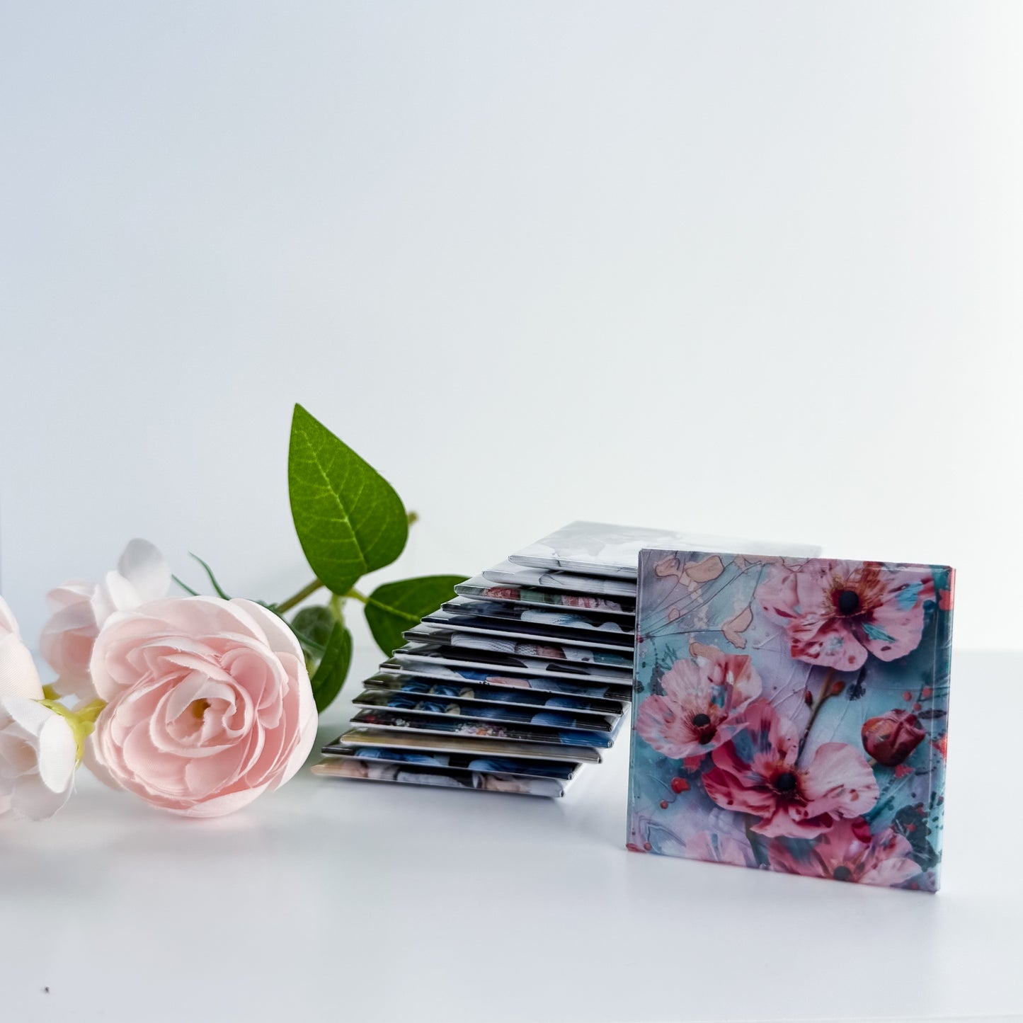 Stack of floral photo magnets with a pink rose on a light background