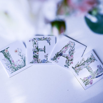Floral alphabet magnets spelling 'Leah' on a white surface with blurred background