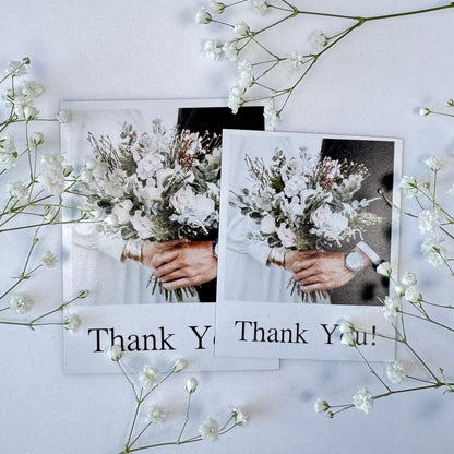 Two photo magnets with hands holding flowers and 'Thank You!' text, surrounded by white flowers on a light background.