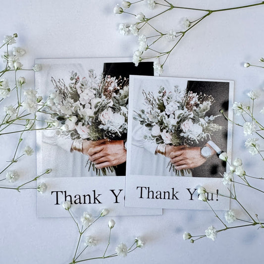 Two photo magnets with hands holding flowers and 'Thank You!' text, surrounded by white flowers on a light background.