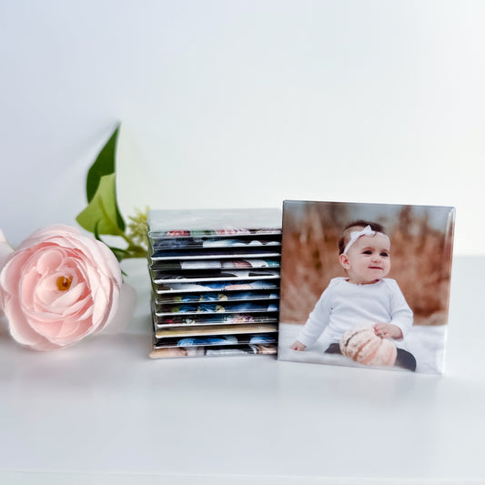 Stack of photo magnets with a baby photo and a pink flower on a white surface