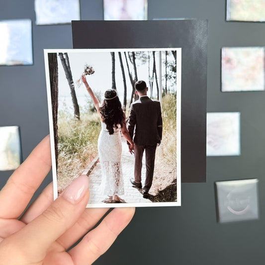 Hand holding a photo  magnet of a couple walking together in a forest.